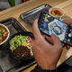Person taking picture of noodle dish with phone
